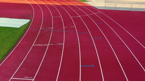 Drone-follows-eight-lane-track-start-line-with-light-across-red-empty-rubber