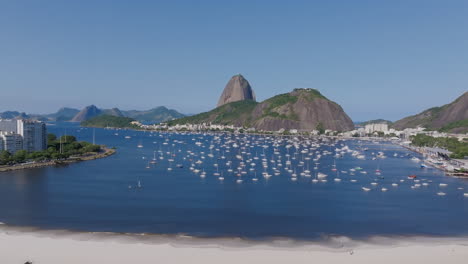 Luftaufnahmen-über-Dem-Strand-In-Der-Bucht-Von-Botafogo-Und-Rio-De-Janeiro,-Brasilien-Mit-Segelbooten-Und-Dem-Zuckerhut-Im-Hintergrund