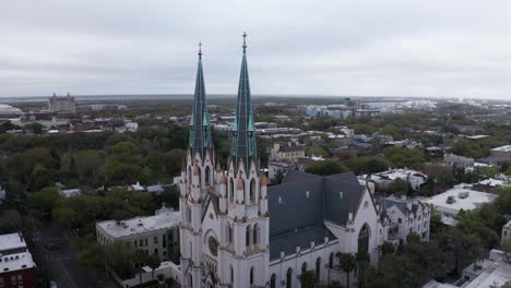 Primer-Plano-Aéreo-De-Las-Agujas-Góticas-En-Lo-Alto-De-La-Basílica-Catedral-De-San-Juan-Bautista-En-Savannah,-Georgia