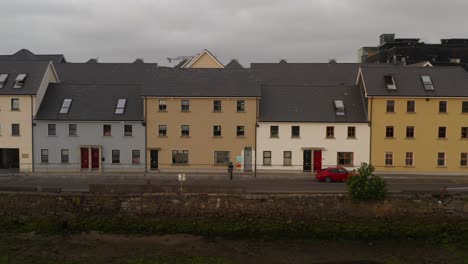 Orbit-aerial-captures-colorful-houses-along-the-iconic-Long-Walk,-Galway-City