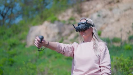 Woman-use-googles-and-rc-motion-control-to-fly-FPV-drone,-blurry-nature-behind