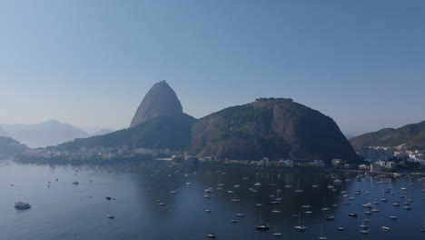 Slow-aerial-footage,-pushing-towards-Sugarloaf-mountain-in-the-daytime-with-Botafogo-Bay-water-underneath