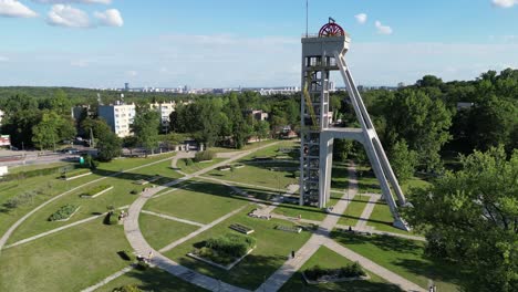 Historical-President-mine-shaft-during-a-beautiful-summer-day-surrounded-by-lush-greenery,-grass,-and-trees-under-a-blue-sky