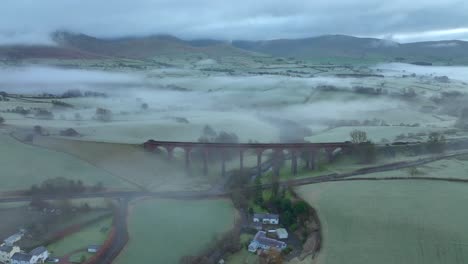 Viaducto-De-Piedra-Abandonado-Puente-órbita-Lenta-Mostrando-Niebla-Y-Niebla-Con-Montañas-Bajas-Distantes-Al-Amanecer-En-Invierno