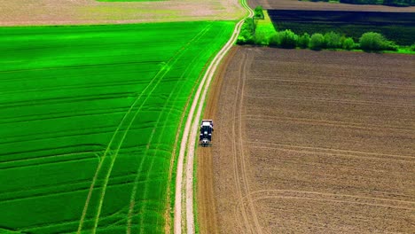 Aerial-View-of-Tractor-Driving-Between-Green-and-Brown-Farmland-in-Countryside