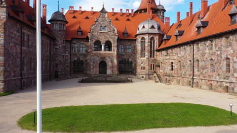 Drohne-Steigt-Auf-Fahnenmast-Zur-Lettischen-Nationalflagge,-Um-Burg-Cesvaines-Zu-Errichten