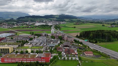 Hünenberg,-Suiza-Con-Exuberantes-Campos-Verdes-Y-Edificios-Bajo-Un-Cielo-Nublado,-Vista-Aérea