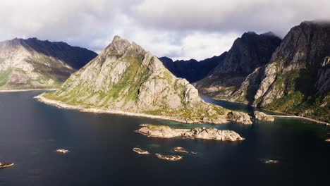Aerial-orbit-around-the-Lofthaugen,-with-an-amazing-rainbow-in-the-background,-near-Henningsvær,-Lofoten-Islands,-Norway