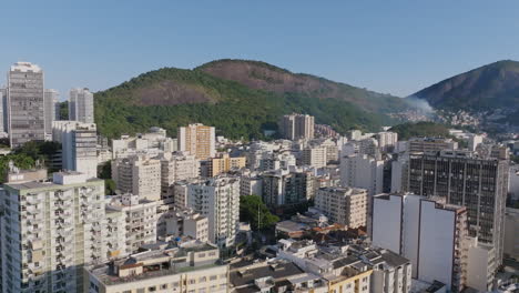 Breite-Luftaufnahmen-über-Den-Wohnhäusern-Des-Stadtteils-Botafogo-In-Rio-De-Janeiro-Mit-Einem-Feuer-In-Einer-Favela-Im-Hintergrund