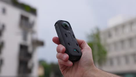 Insta360-X4-Action-Kamera-Zeigt-Sich-Mit-Einer-Hand-Vor-Tageslichthintergrund