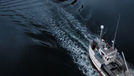 Luftaufnahme-Eines-Fischerboots,-Das-Unter-Der-Flakstadbruene-Brücke-In-Den-Hafen-Zurückkehrt,-In-Der-Nähe-Von-Fredvang,-Lofoten-Inseln,-Norwegen