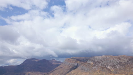 Mountains-under-a-dramatic-vast-cloudy-sky-at-Beinn-Eighe-in-Scotland,-aerial-view