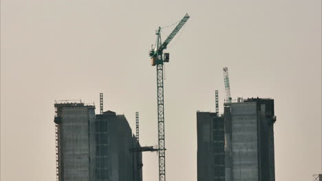 Timelapse-shot-of-a-tower-crane-and-construction-lifts-bringing-equipment-and-people-up-and-down-a-high-rise-building-that-is-in-construction