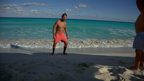 Fit-mexican-latin-man-wearing-shorts-showing-and-pointing-the-waves-to-his-young-son-at-a-beach-in-Cancun-Mexico