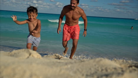 Slow-motion-of-a-mexican-latin-brunette-boy-running-away-from-his-father-at-the-beach-being-chased-laughing-and-having-fun-in-Cancun