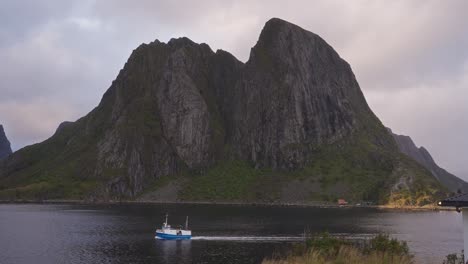 Slow-motion-of-a-fisherman's-boat-passing-in-front-of-the-mountains-of-Hamnøy-near-Reine,-Lofoten-Islands,-Norway