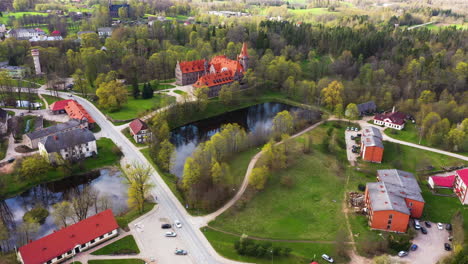 Cesvaines-castle-and-surrounding-forest-on-spring-day-in-peaceful-town,-aerial-orbit