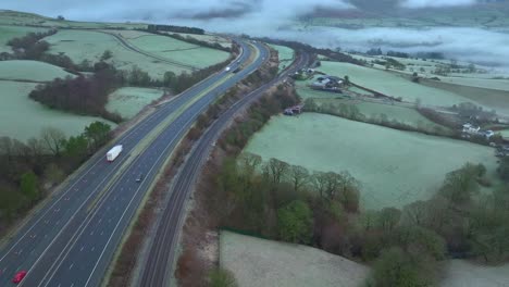 M6-highway-with-light-traffic-at-dawn-in-winter-with-slow-pan-up-revealing-fog-in-shallow-valley-and-low-cloud-on-hills