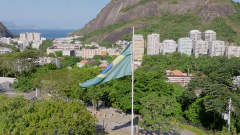 Close-up-slow-motion-aerial-footage-rotating-around-the-flag-of-Brazil-moving-in-the-wind-at-the-Yitzhak-Rabin-Park-in-Rio-de-Janeiro