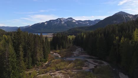 Scenic-Aerial-view-flying-over-creek-in-between-Evergreen-forest-and-mountains-in-the-background-at-Gold-Creek-Pond-in-Washington-State