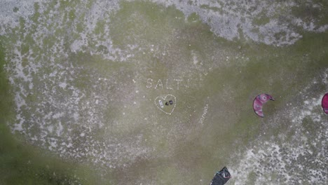 A-heart-shaped-kite-layout-on-los-roques-island-grass,-aerial-view