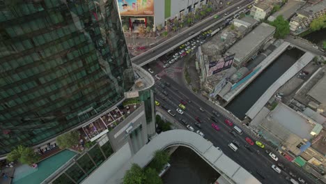 Vista-Aérea-Del-Vibrante-Tráfico-Rodado-Cerca-De-Los-Imponentes-Rascacielos-De-Bangkok,-Capturando-La-Esencia-Dinámica-De-La-Vida-Urbana-En-La-Capital-De-Tailandia.