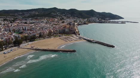 The-city-and-coastline-of-sitges,-spain-on-a-sunny-day,-aerial-view