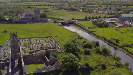 Ruinas-Del-Convento-De-Claregalway-Y-Castillo-En-Un-Día-Soleado-Y-Vibrante,-Aéreo-Por-El-Río-Clare