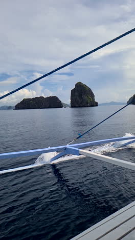 Vertical-Video,-Traditional-Bangka-Filipino-Boat-Sailing-Between-Scenic-Islands-and-Rocks,-Slow-Motion
