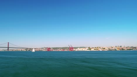 Vídeo-Timelapse-Del-Icónico-Puente-25-De-Abril-Con-El-Paisaje-Urbano-De-Lisboa-Desde-Lejos-A-Través-Del-Río-Tajo-En-Un-Día-Soleado-En-Portugal