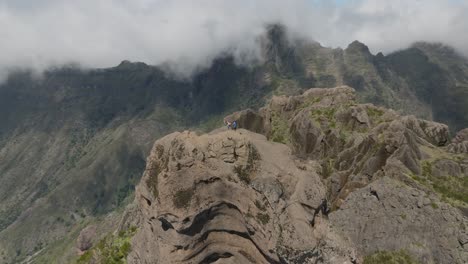 Crazy-hikers-on-large-rock-pinnacle-in-scenic-mountain-range-on-sunny-day