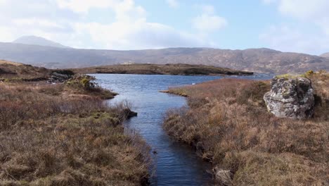 Vista-Panorámica-Del-Paisaje-De-La-Roca-Gneis-Lewisiana-Y-Del-Terreno-Montañoso-Con-Vistas-Al-Agua-Del-Lago-Inver-Y-A-Los-Pastos-Dorados-De-Tussock-En-Las-Tierras-Altas-De-Escocia,-Reino-Unido