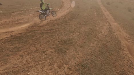 Emocionante-Y-Dramático-Dron-FPV-Sigue-A-Un-Corredor-De-Motocross-En-Una-Pista-De-Tierra