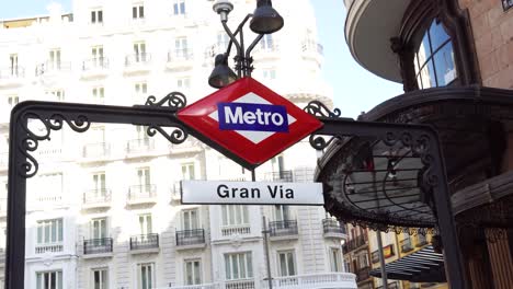 Gran-Vía-Metro-Señal-De-La-Estación-De-Metro-Con-Edificios-De-Fondo-En-El-Centro-De-Madrid