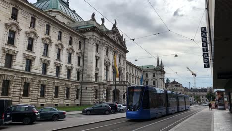 Tram-Passing-Great-Palace-of-Justice-from-Karlsplatz,-Munich,-Germany