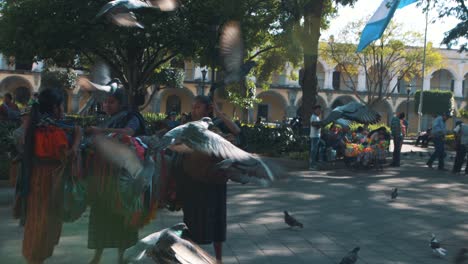 Pigeons-flying-,-mayan-local-ladies-and-guatemalan-flag-waving-in-Slow-motion-in-Antigua-Guatemala-central-park