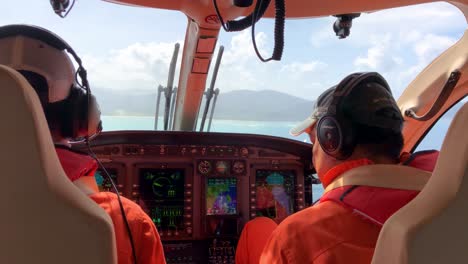 Hubschrauber-Cockpit-Mit-Zwei-Piloten-Während-Des-Anflugs-Auf-Den-Flughafen-Mit-Herrlichem-Bergblick