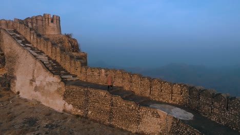 Drone-flight-at-ranikot-fort-in-sindh-pakistan---Man-walking-on-historical-ruin-wall