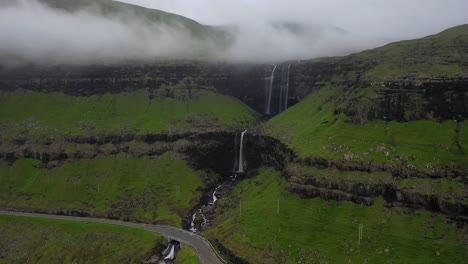 Fossá-Waterfall-over-sea-cliffs-on-Faroe-Islands-coastline,-aerial-pull-away-reveal