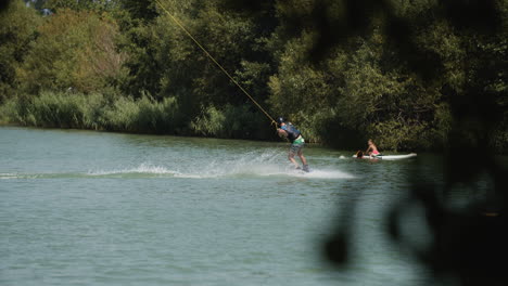 Tracking-shot-of-male-water-skier-skiing-on-natural-lake-during-sunny-day