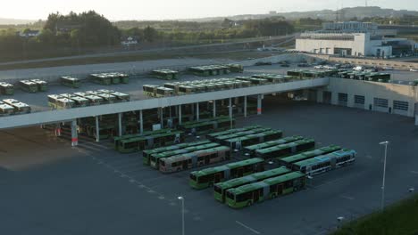 Vista-Aérea-De-Drones-Del-Estacionamiento-De-Autobuses-Eléctricos-Verdes-En-Los-Suburbios-De-Stavanger,-Noruega