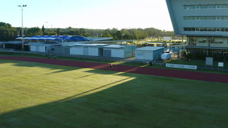 Aerial-4K-Drone-Over-Sports-Field-With-Man-Running-Laps-On-Race-Track-With-Afternoon-Sunlight