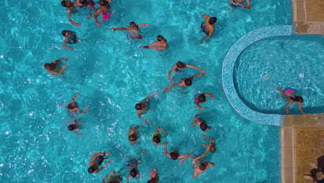 Top-view-drone-shot-of-swimming-pool-in-hotel-complex-with-kids-playing