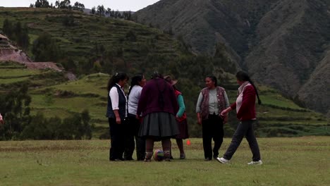 Andean-local-women-playing-female-football-in-Chinchero,-Cusco,-Perú-with-tourist