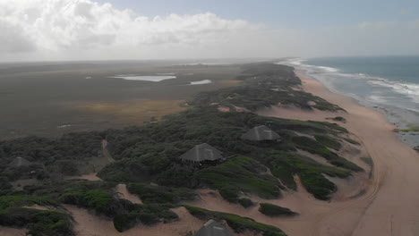 Luftaufnahme-Von-Luxuriösen-Lodges-Im-Busch-Am-Sandstrand-In-Mosambik