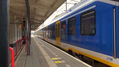 An-electric-train-in-Holland-departs-from-a-platform-in-a-small-town