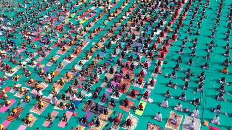 Aerial-footage-of-people-performing-Yoga-in-a-stadium-at-Ahmednagar,-India-on-the-occasion-of-International-Yoga-Day-along-with-school-students