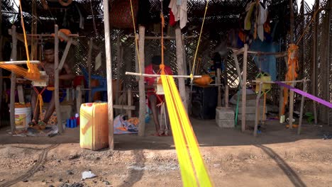 An-outdoor-weaving-hut-protected-from-the-sun-by-bamboo-and-palm-leaves-is-where-weavers-make-the-colorful-Kente-cloth-for-traditional-African-Clothing