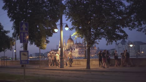 Menschen-Gehen-Mit-Blick-Auf-Das-Ungarische-Parlament-Bei-Sonnenuntergang