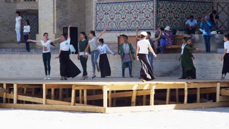 Young-women-rehearse-for-Silk-and-Spices-Festival-in-front-of-Kalon-mosque-in-Bukhara,-Uzbekistan